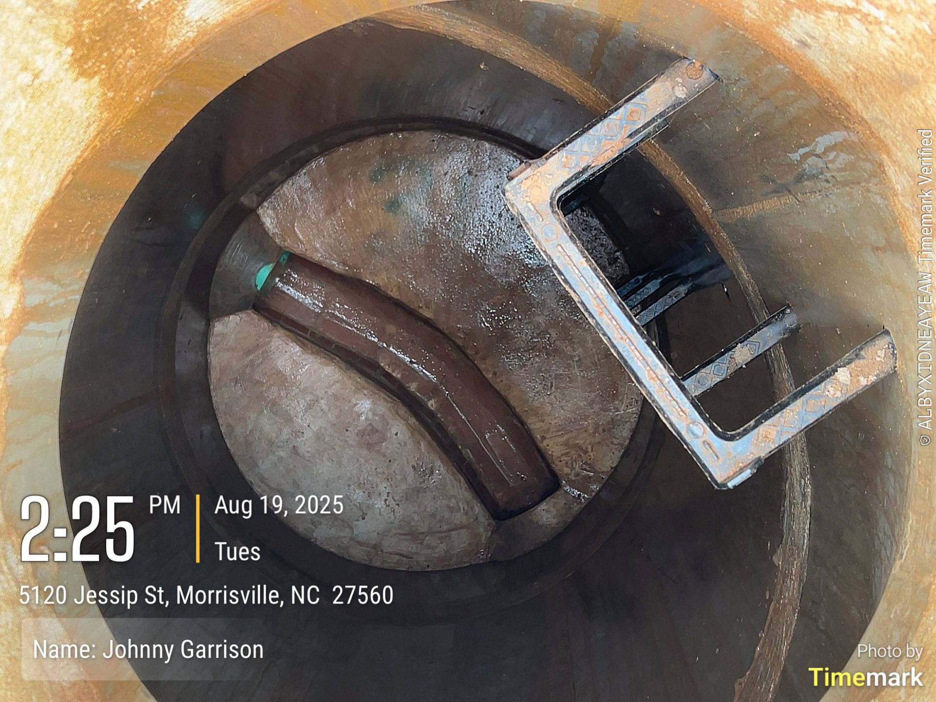 Looking down into a well with a bent pipe and metal frame.