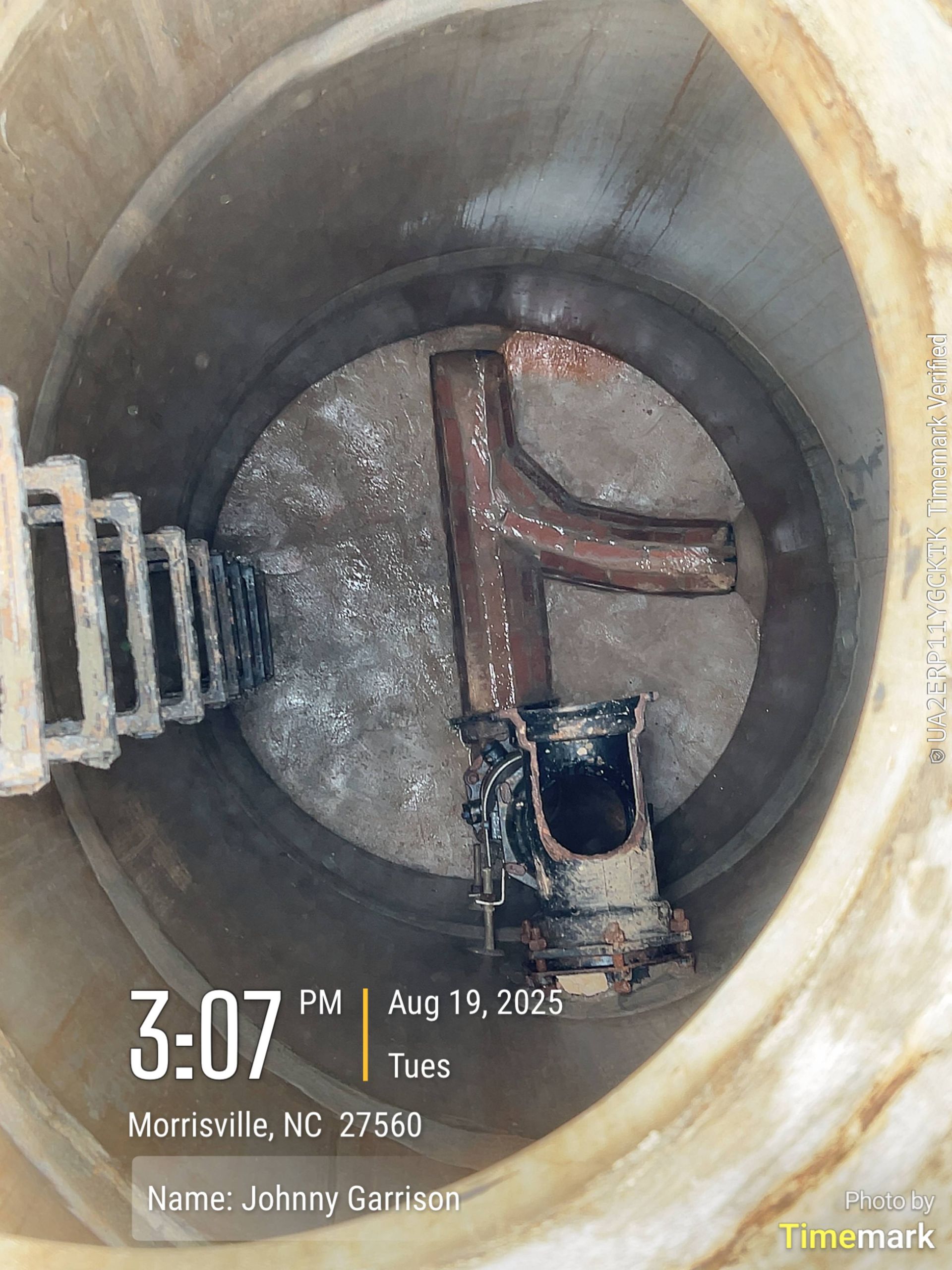 Inside a white tank with a brown pipe, possibly a septic system inspection.