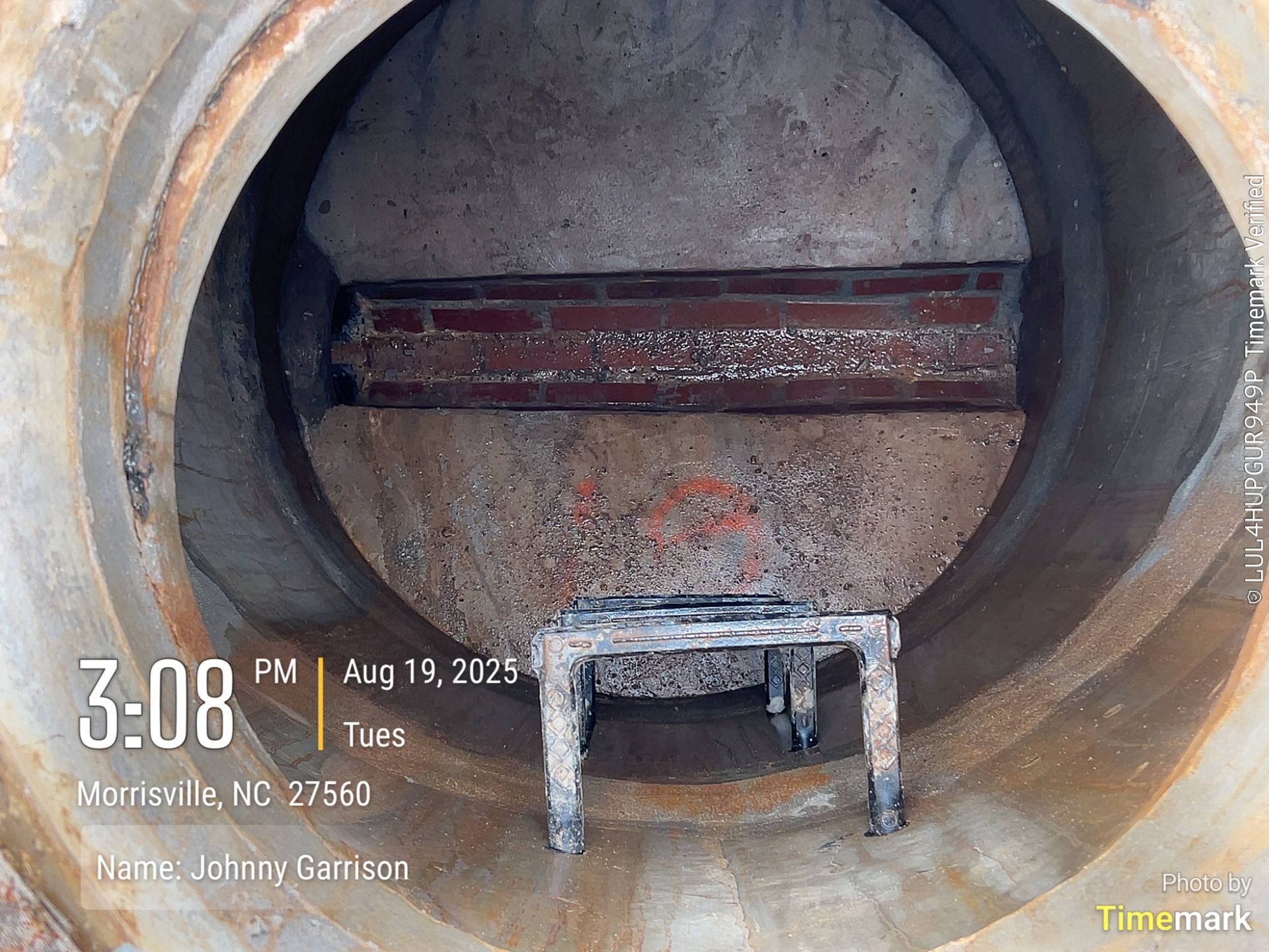 Inside a concrete pipe, a brick wall section is visible. A small table sits below it.