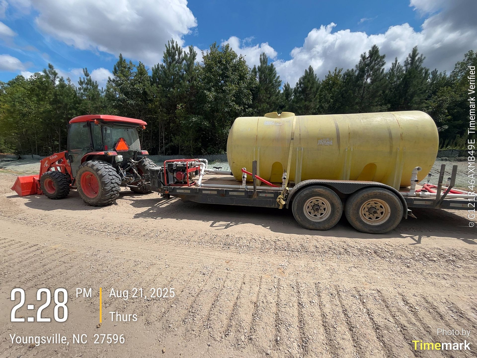 A tractor pulling a yellow water tank on a trailer in Youngsville, NC. The sky is blue.