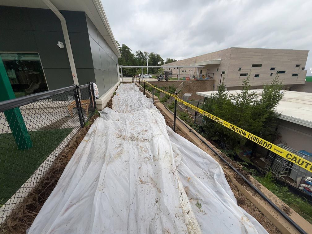 A white tarp covers a narrow walkway next to a building, caution tape across the right.