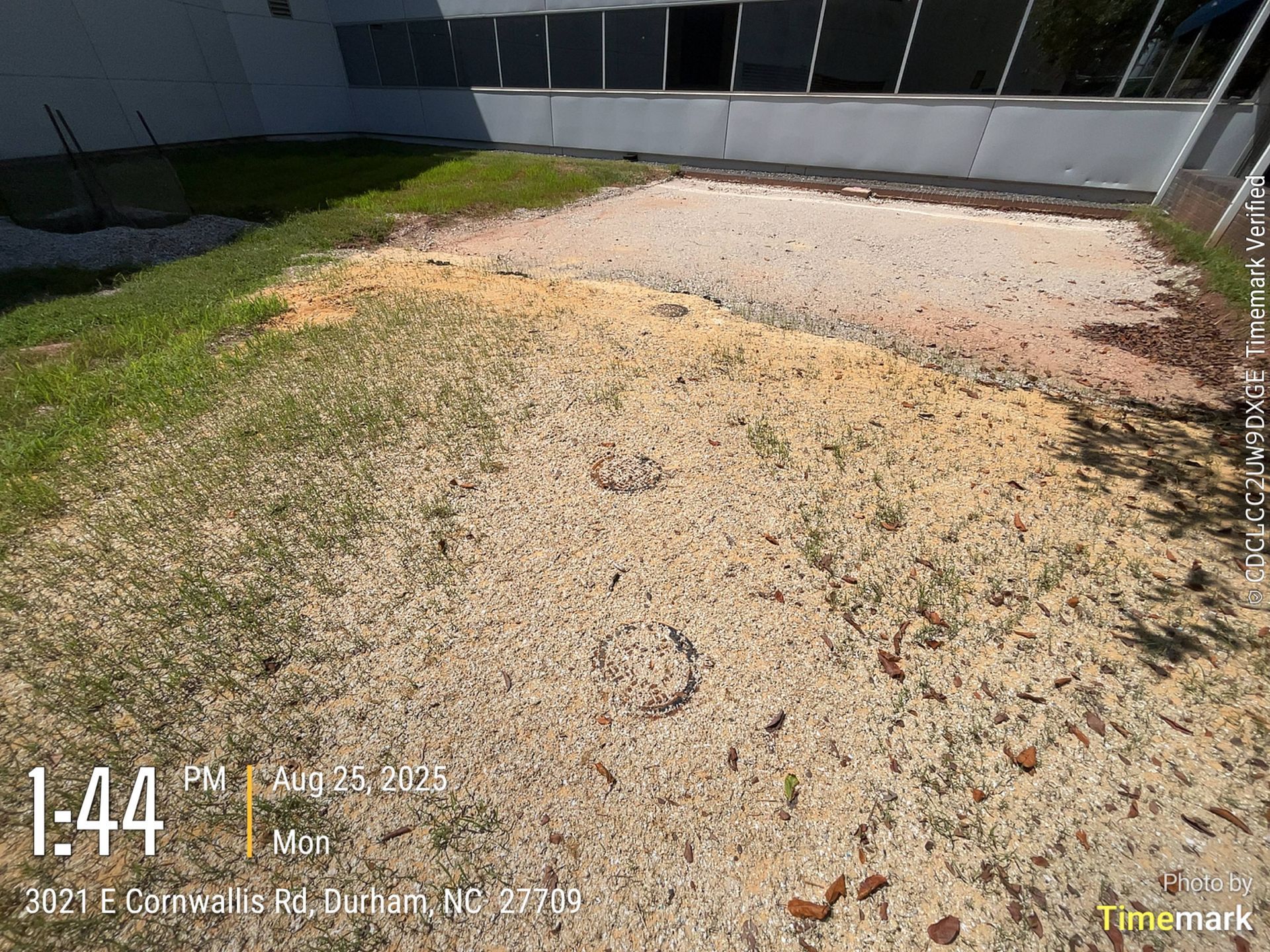 Ground with circular markings, dirt and patches of grass, next to a building, Durham NC.