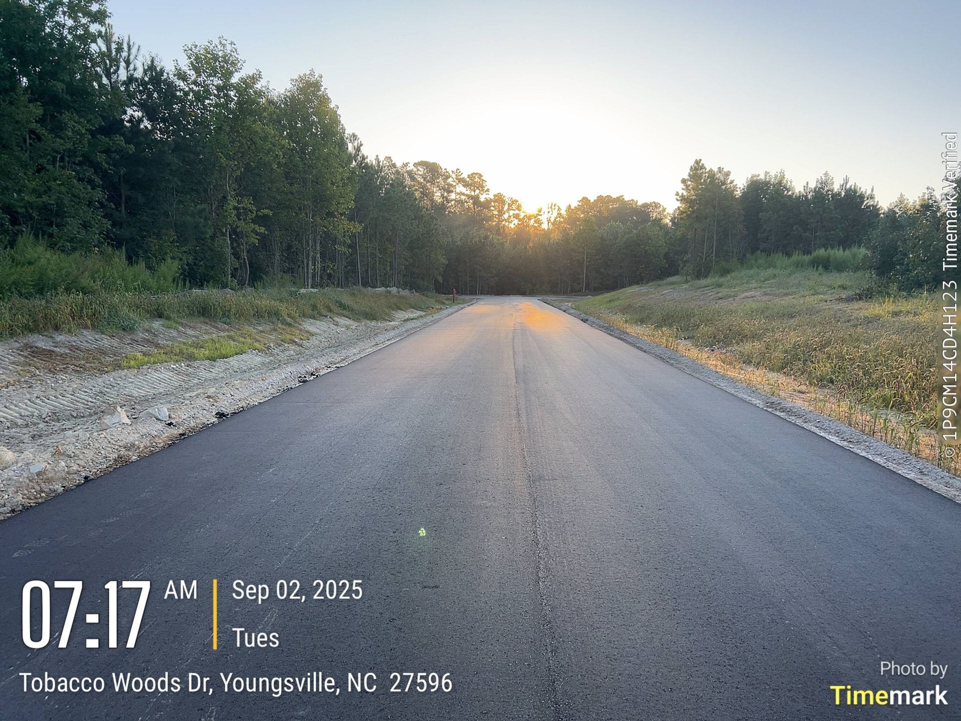 Paved road leading to sunrise through trees, timestamped 07:17 AM Sep 12, 2025, in Youngsville, NC.