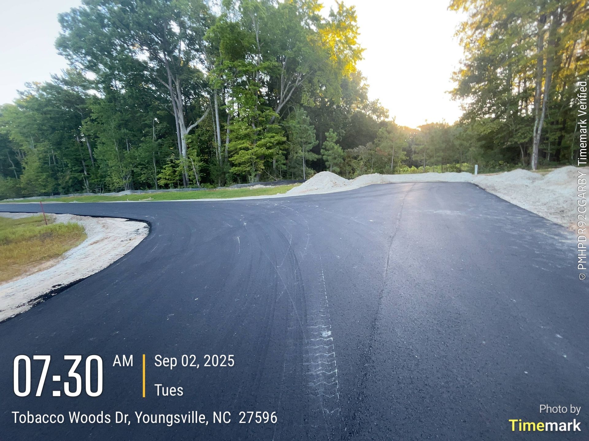 Newly paved road in Youngsville, NC, with trees in the background and the sun rising. Time and date stamp.