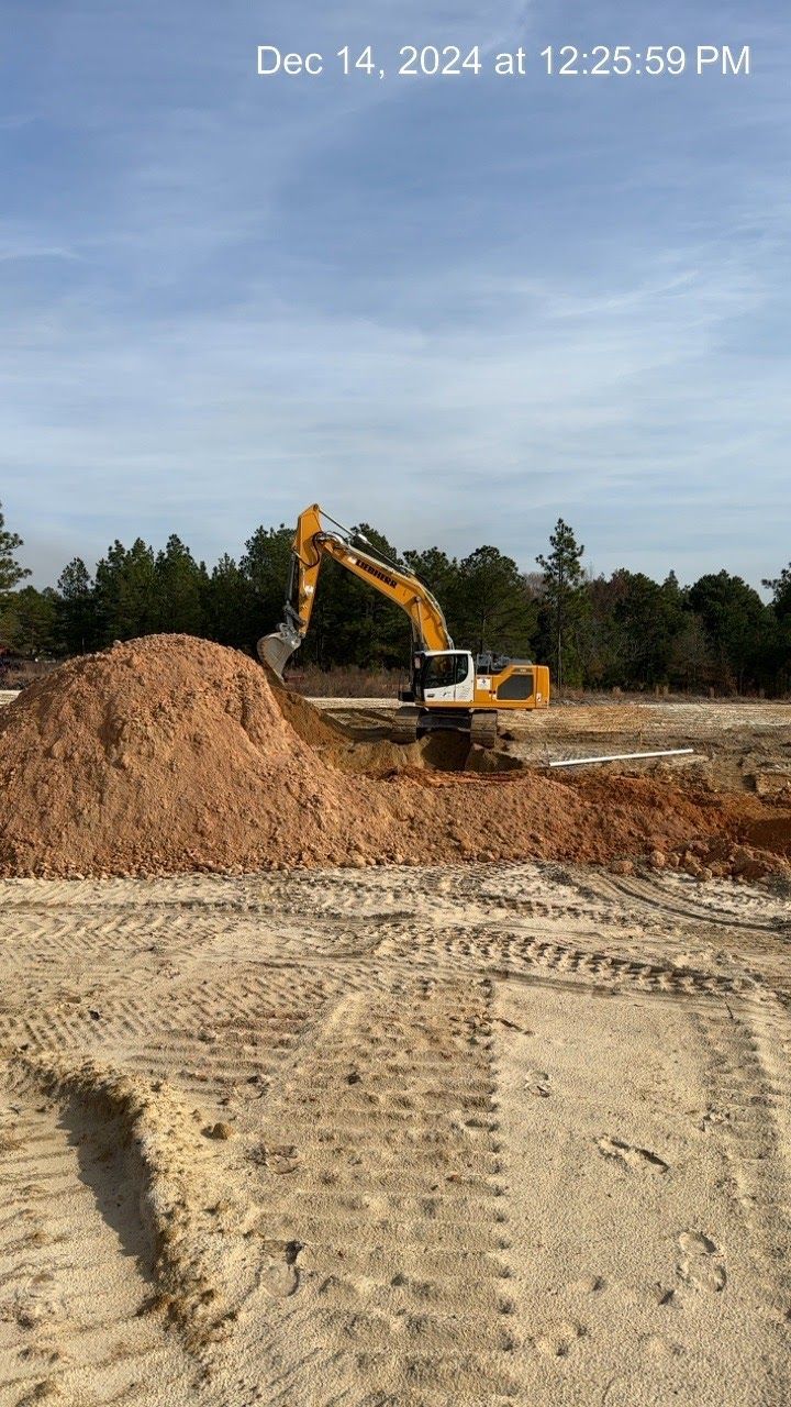 Excavator at work on a construction site, moving dirt on a sunny day.