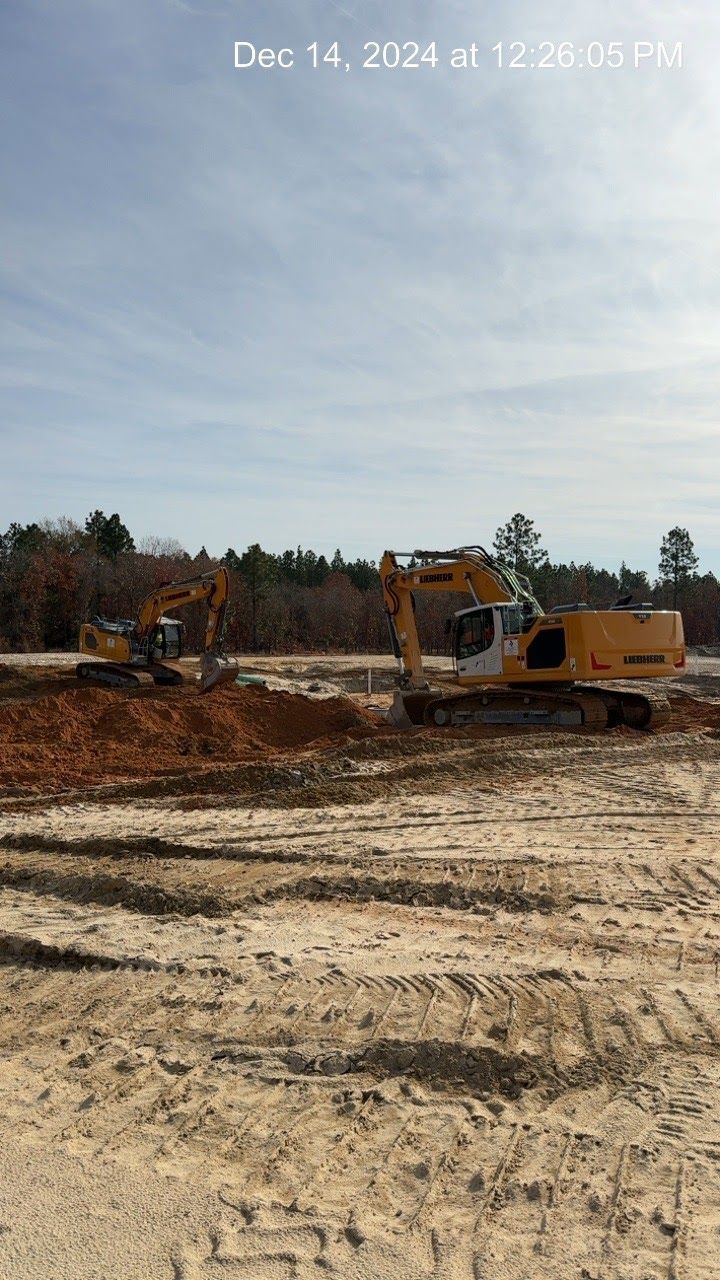 Two yellow excavators working on a construction site under a blue sky.