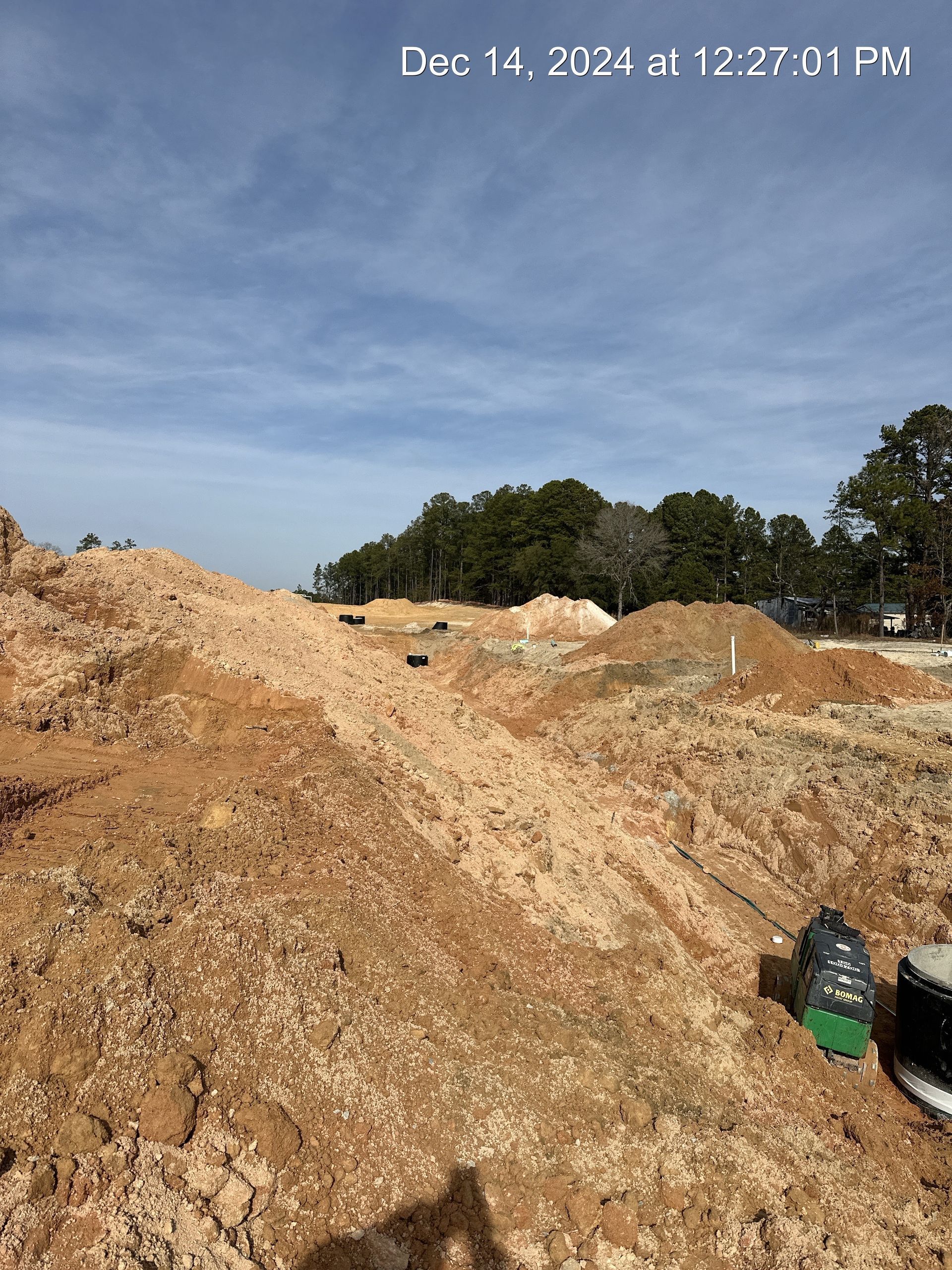 Construction site with piles of dirt under a blue sky; Dec 14, 2024.