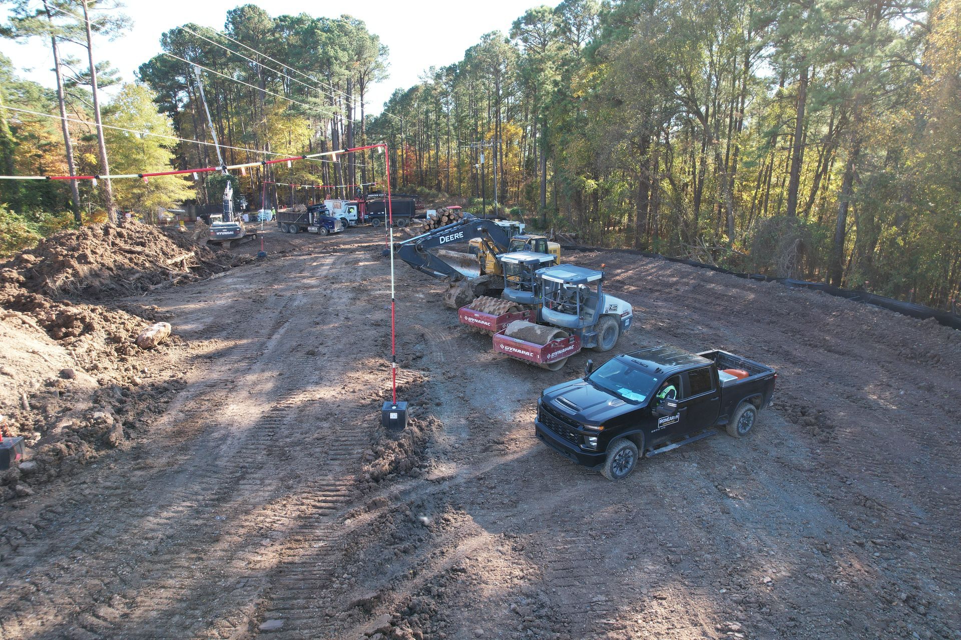 Construction site with vehicles, including a black pickup truck, and heavy machinery, preparing land.