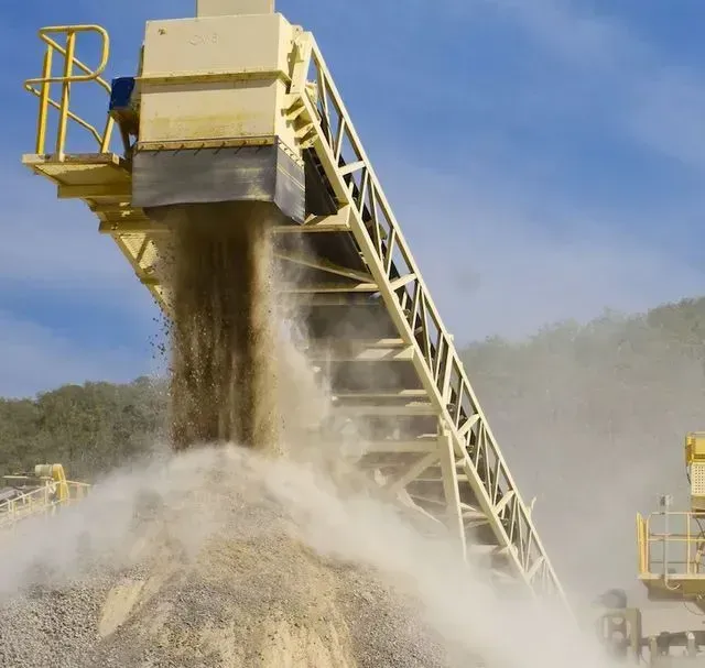 A Yellow Conveyor Belt is Carrying a Pile of Dirt — Ostojic Group in Berrimah, NT