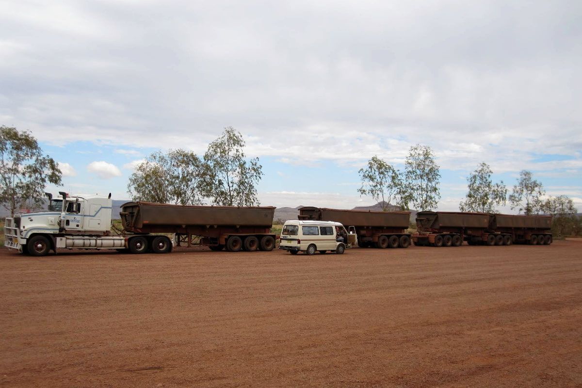 A White Van is Parked Next to a Row of Trucks in a Dirt Field — Ostojic Group in Berrimah, NT