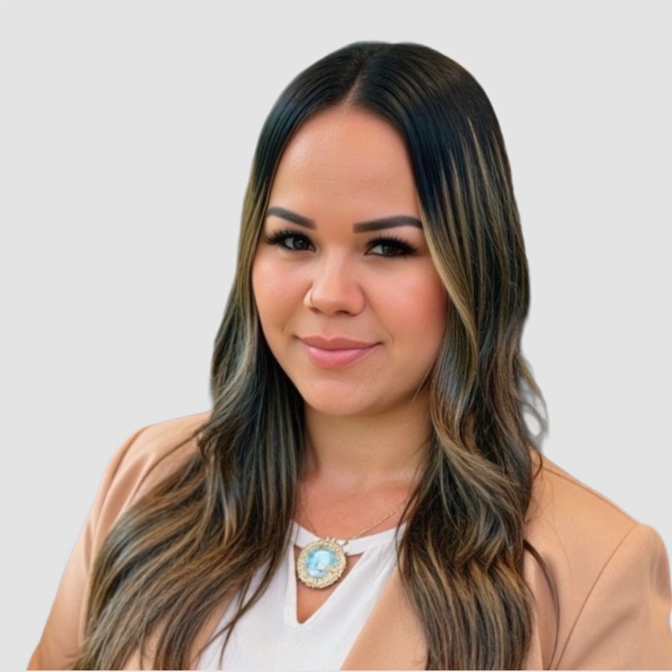 Woman with long highlighted hair wearing a tan blazer and necklace, smiling.