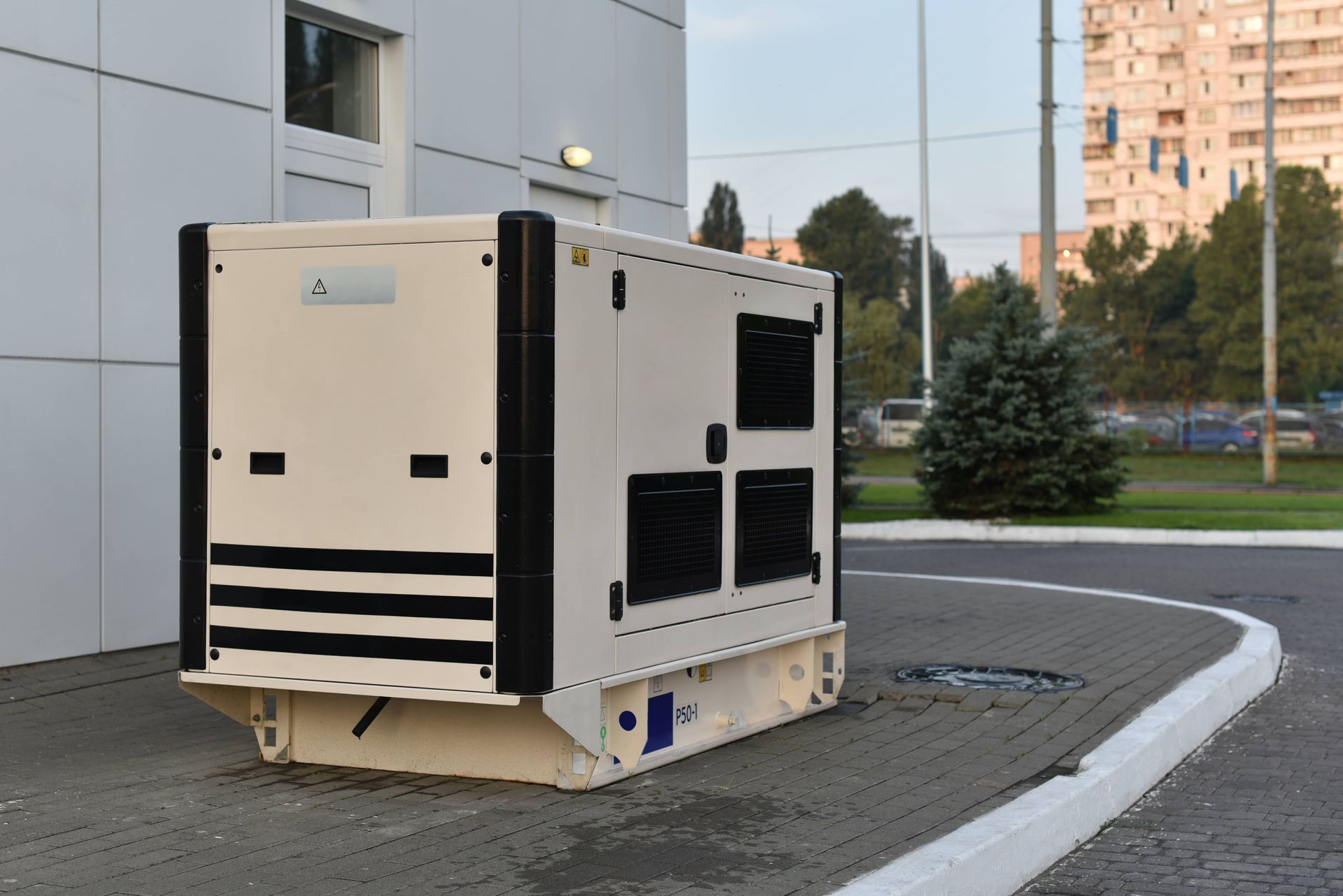 A large white and black generator is parked in front of a building.