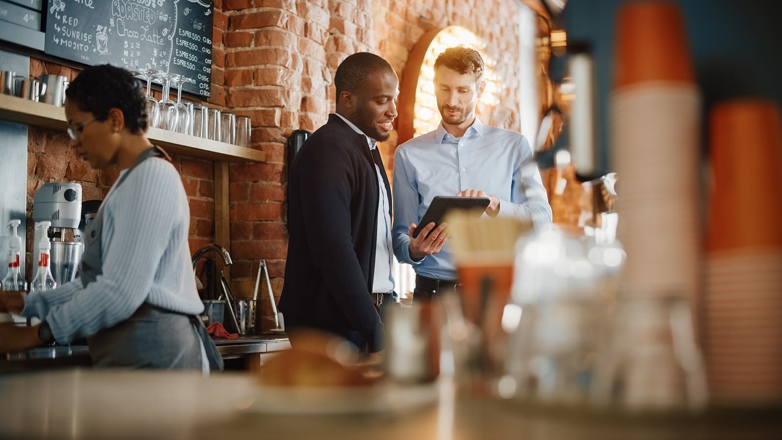 A group of people are standing around a table talking to each other.