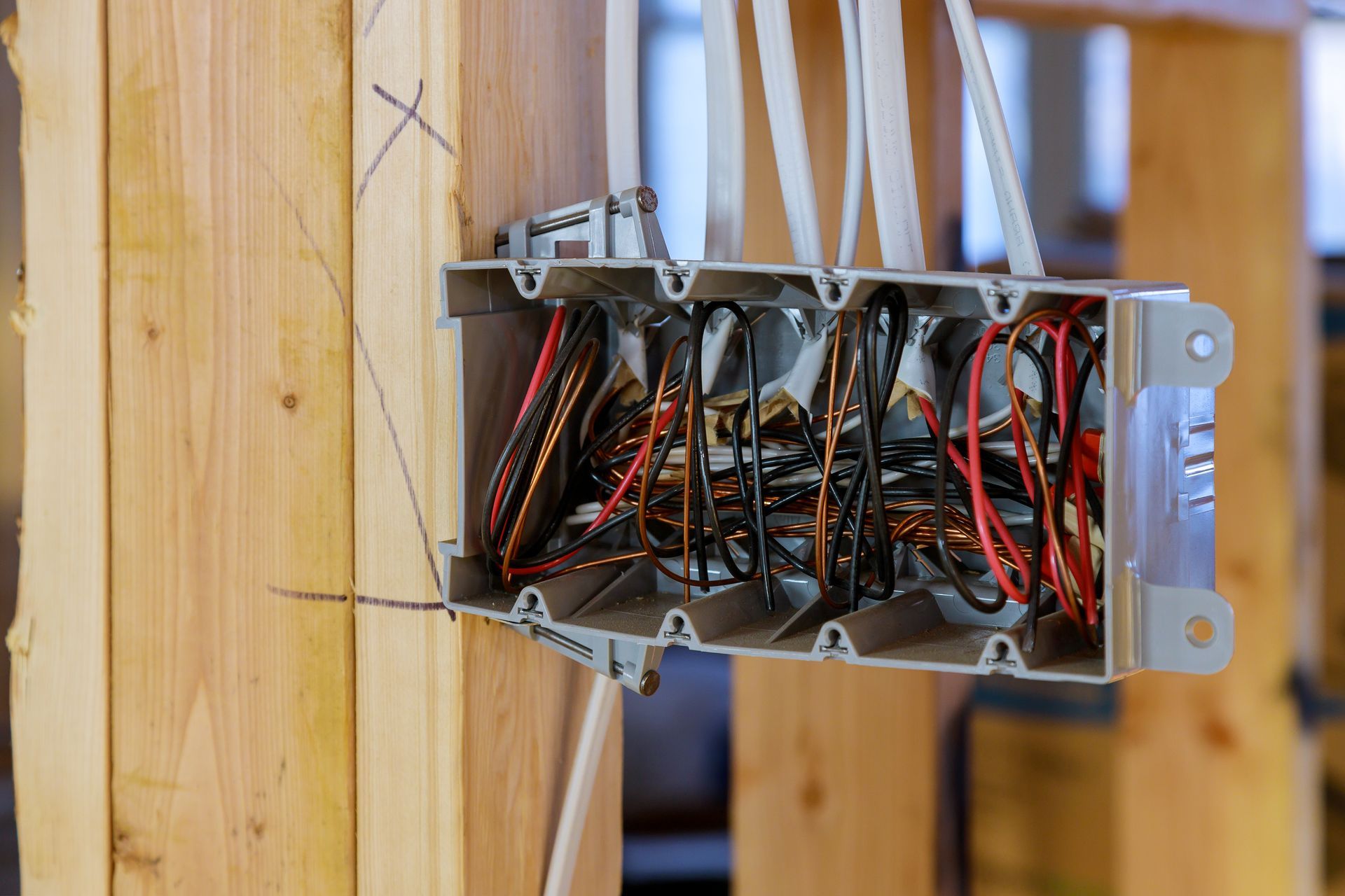 Electrical wiring box installed on wooden studs; black, red, and white wires.