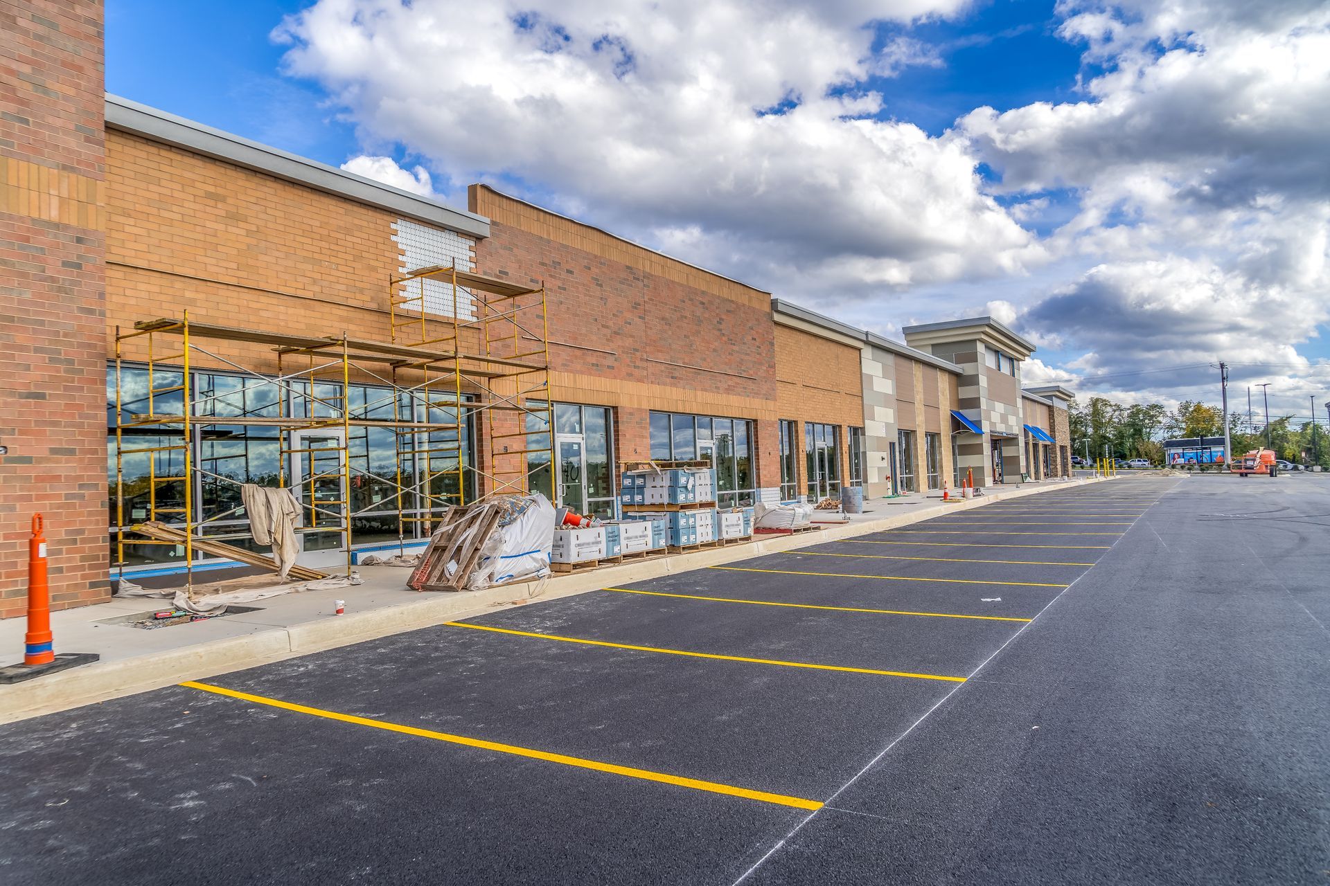 A row of brick buildings under construction with a parking lot in front of them.