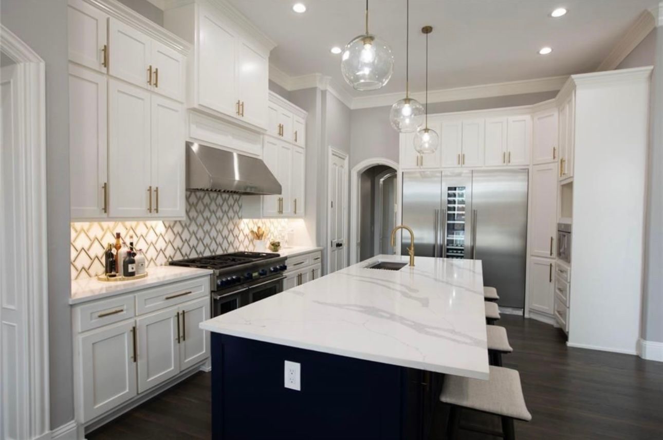 A kitchen with white cabinets , stainless steel appliances , and a large island.