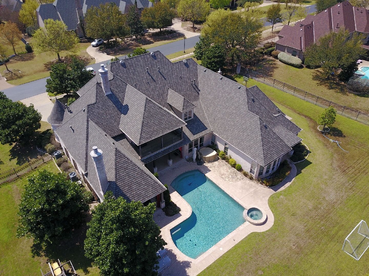 An aerial view of a large house with a large pool in the backyard.