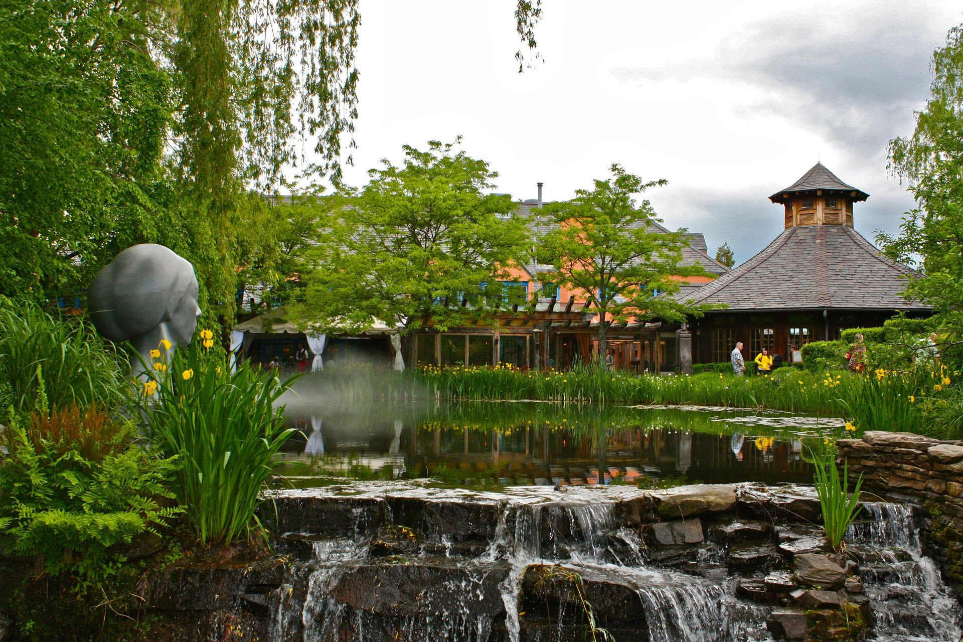 A waterfall in a park with a building in the background