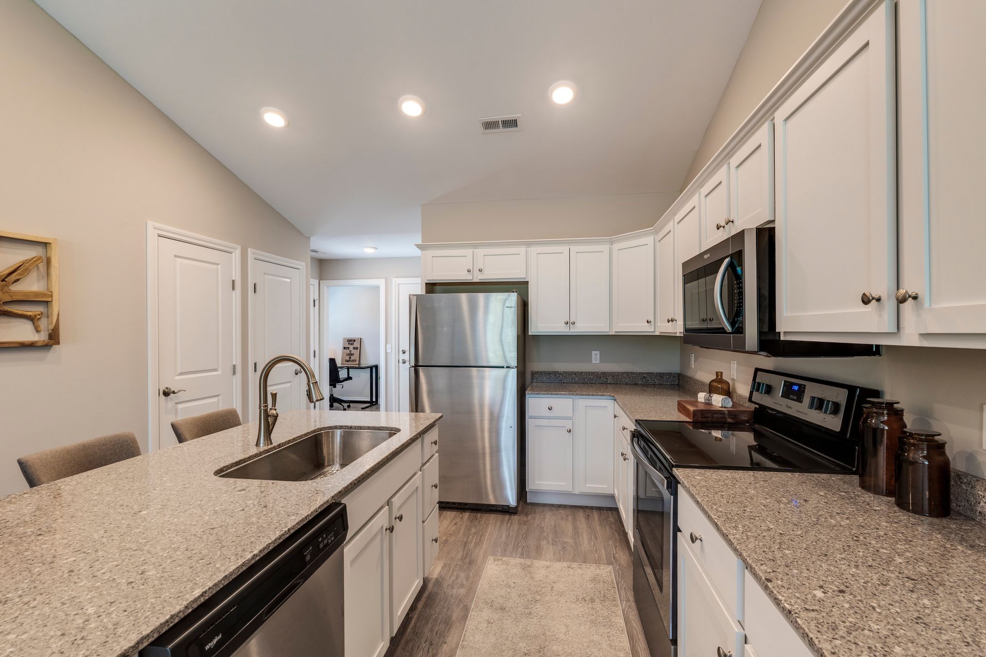 Modern kitchen with white cabinets, stainless steel appliances, and a gray countertop island.