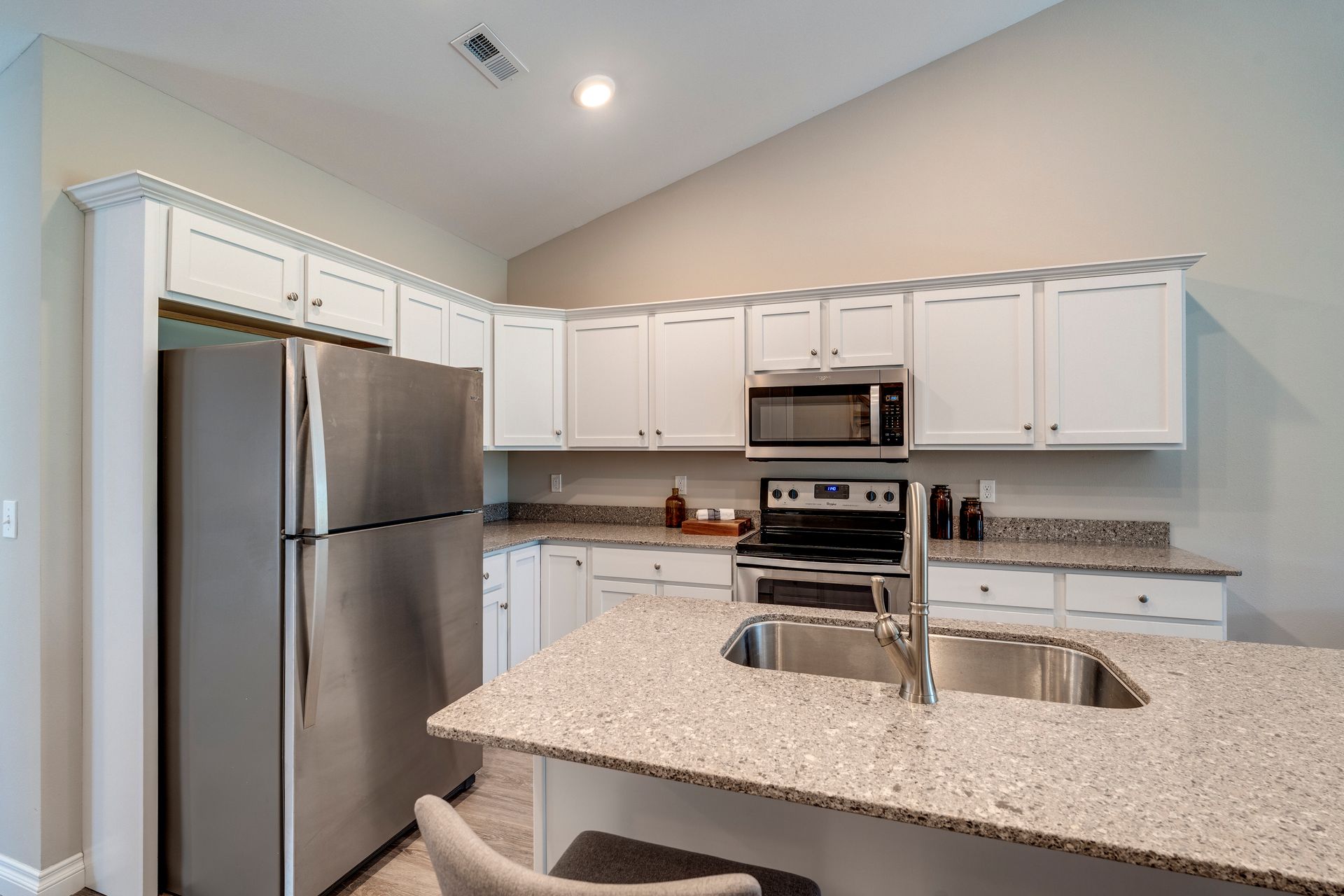 Kitchen with white cabinets, stainless steel appliances, and a granite countertop island.