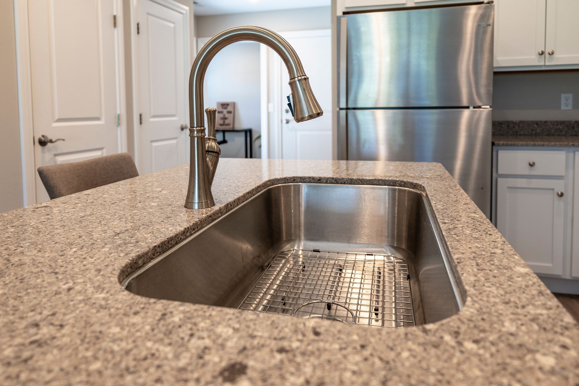 Stainless steel sink in a kitchen island with a granite countertop. A faucet is installed over the sink.
