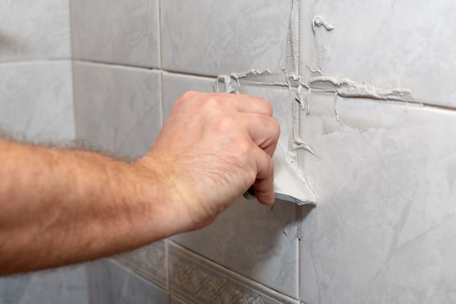 Applying fresh grout to repair wall tile joints. Applying fresh grout to repair wall tile joints.