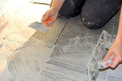 A worker performing grout repair services.