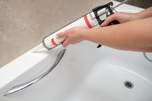 A worker performing grout sealing services. A worker performing grout sealing services.