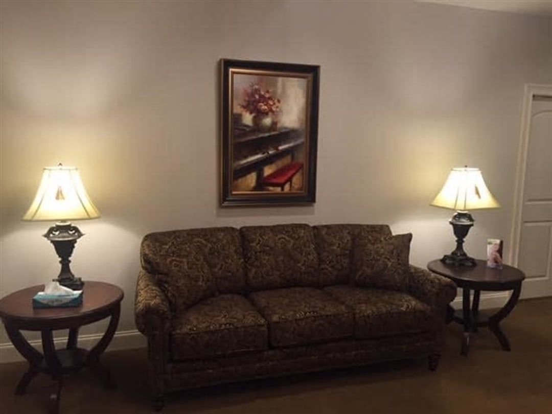A living room with a sofa, two lamps, and an artwork on the wall.