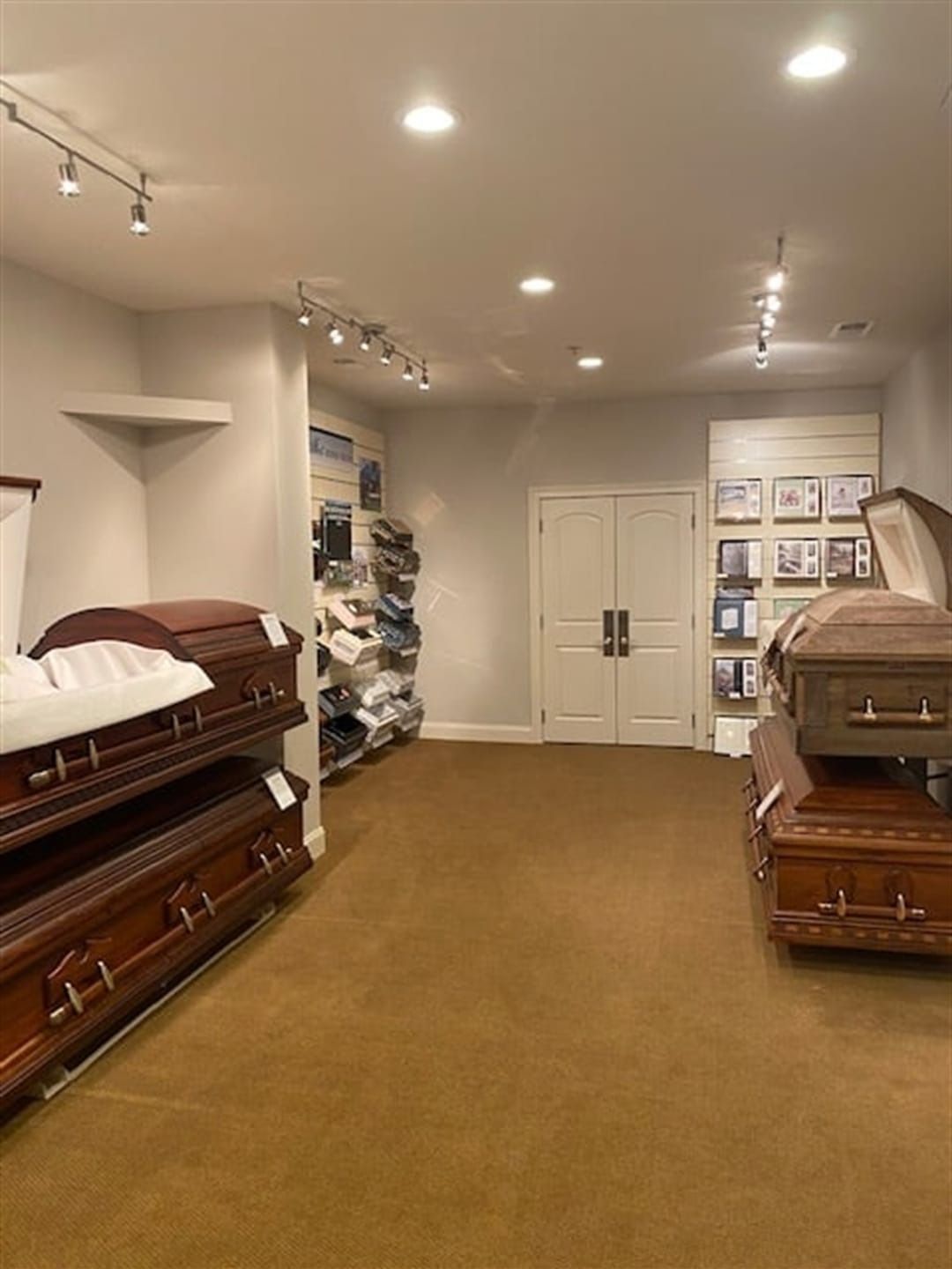 Interior of a funeral home showroom, featuring caskets and merchandise on display.