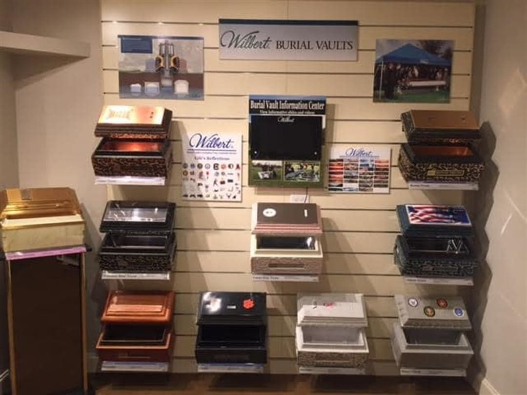 Display of burial vaults with various styles and colors on a showroom wall.