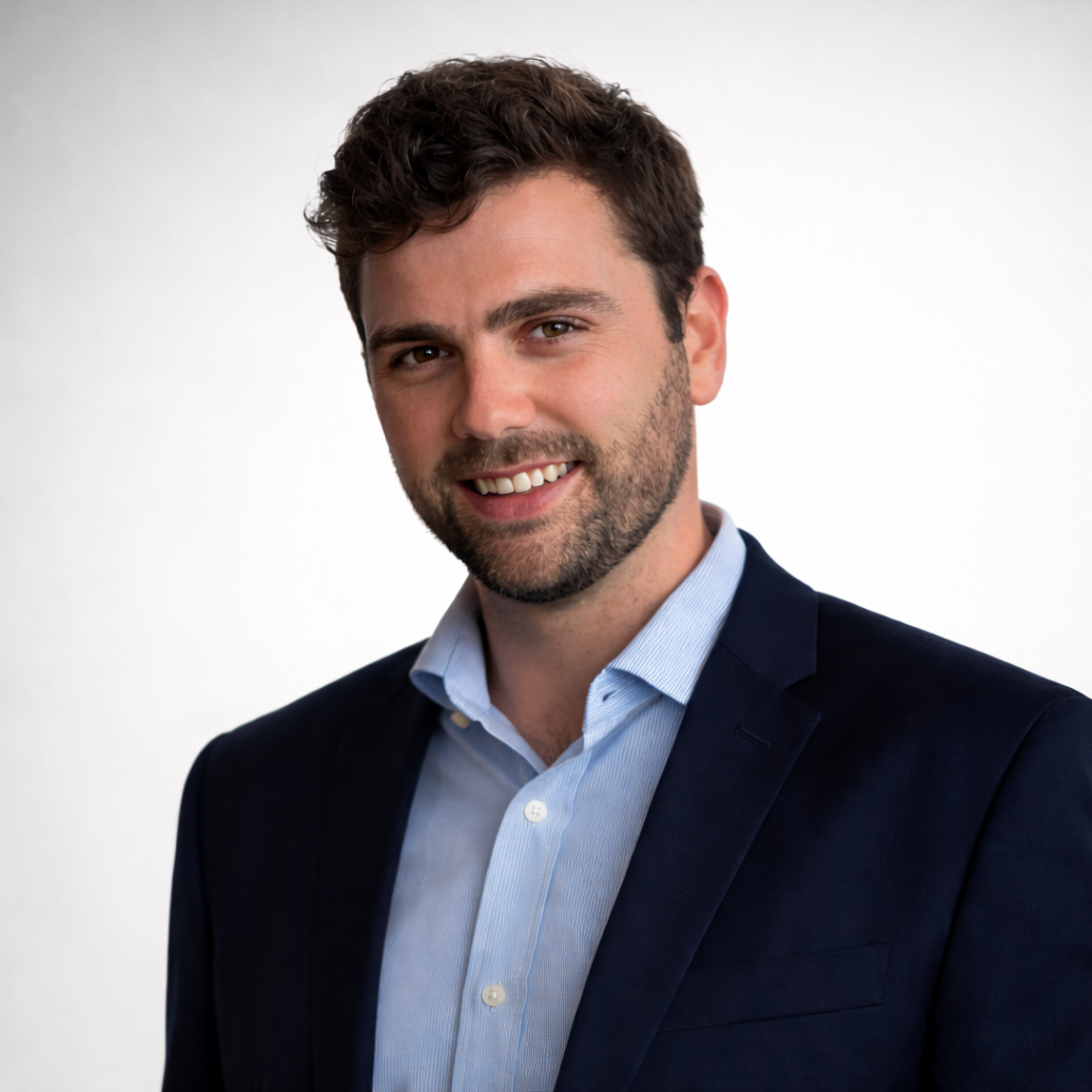 Woman with gray hair smiles, wearing a black top, against a light gray background.