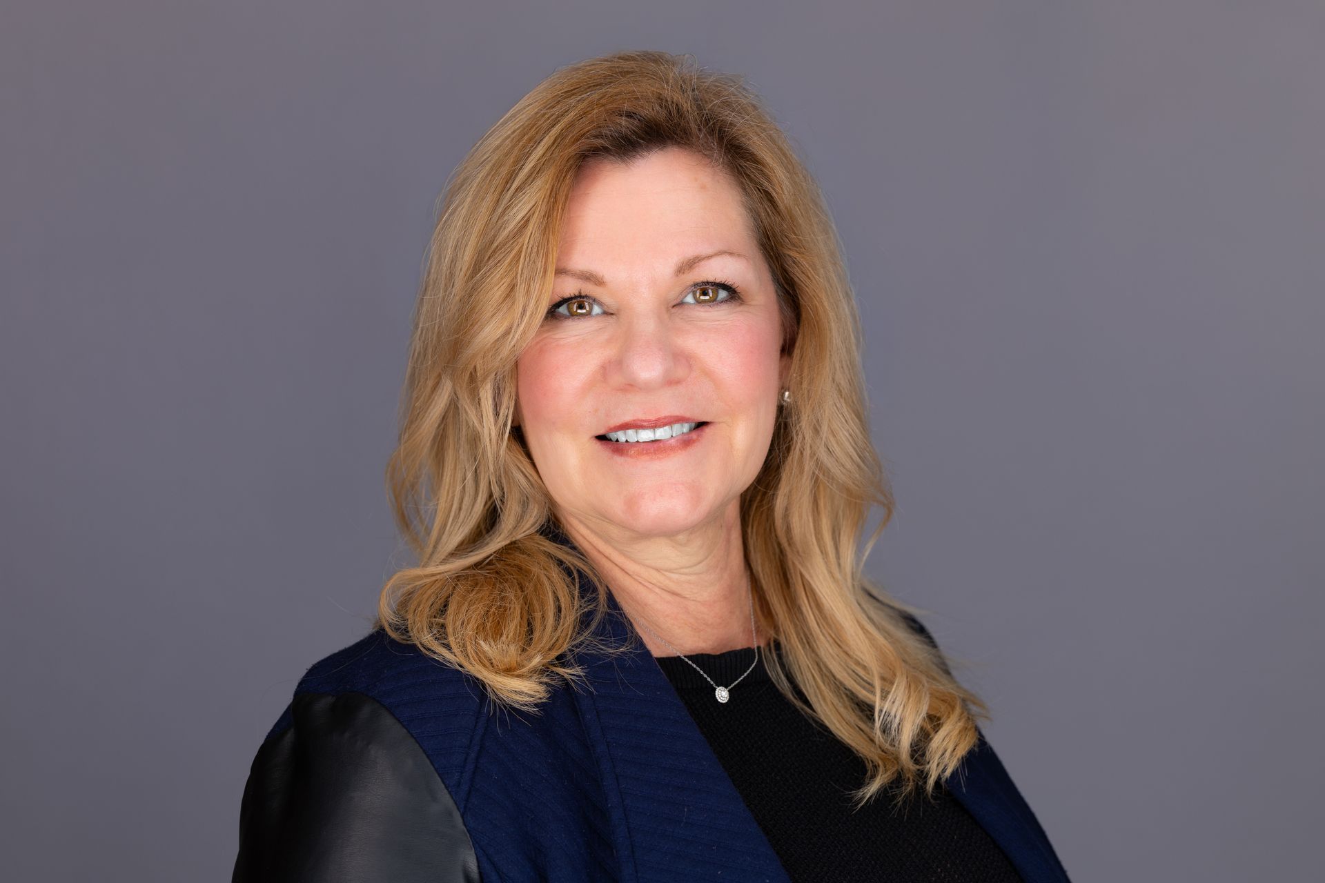Woman with brown hair smiling, wearing a black top.
