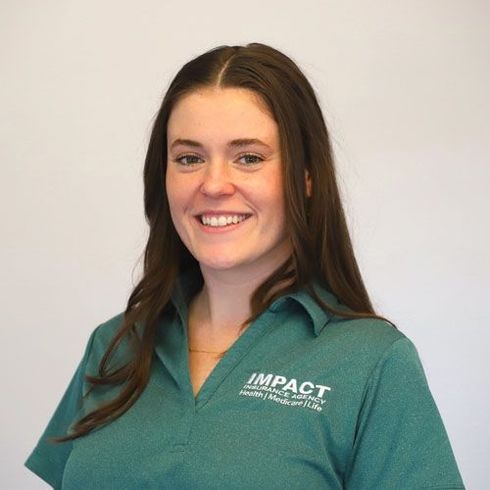 Woman with long brown hair smiles, wearing a green shirt with