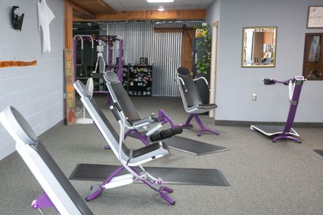 a gym with purple and white equipment and a mirror