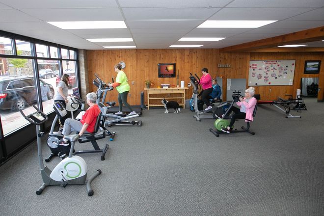 a group of old people are using exercise bikes in a gym
