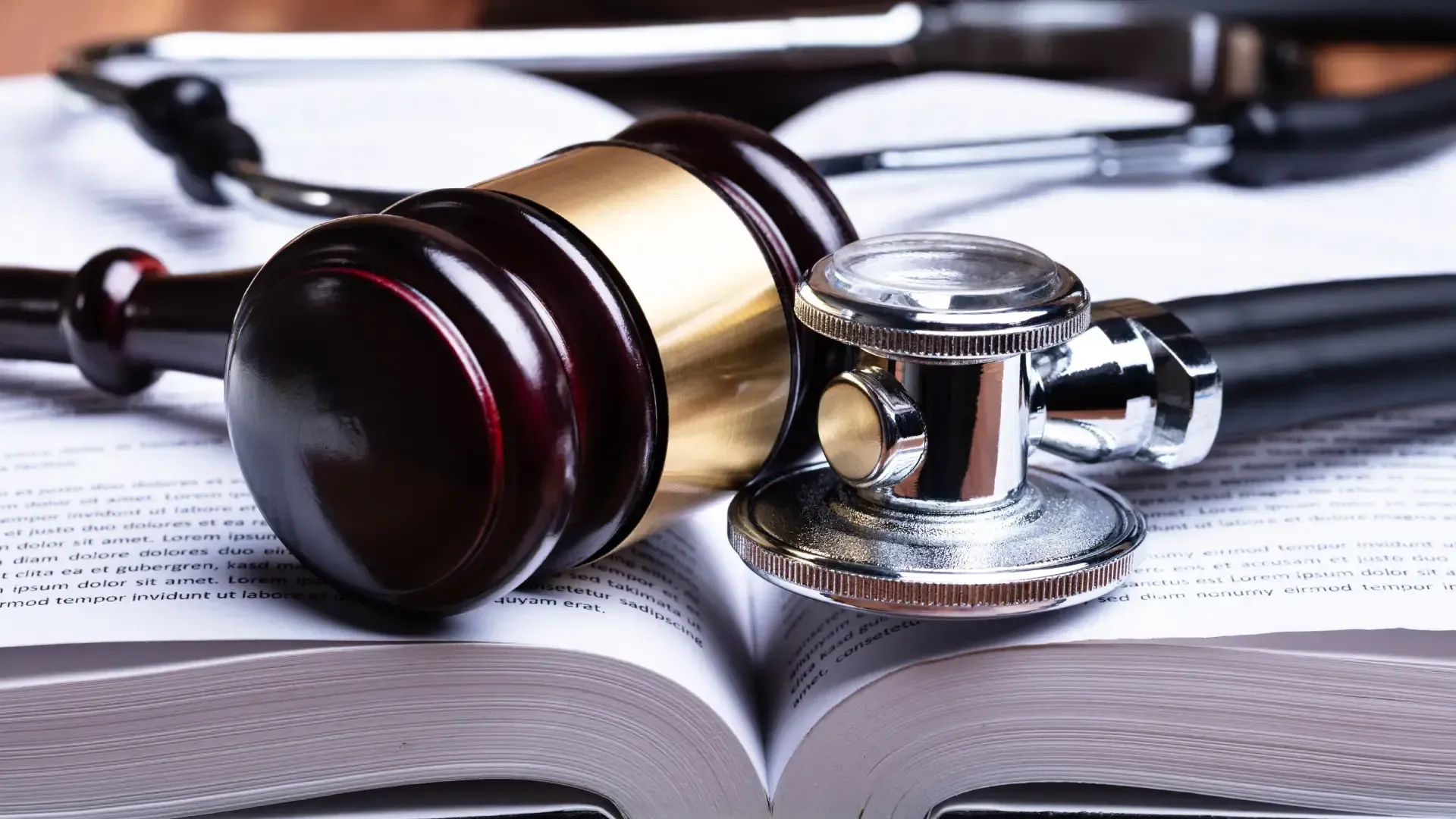 A judge 's gavel and stethoscope are sitting on top of an open book.