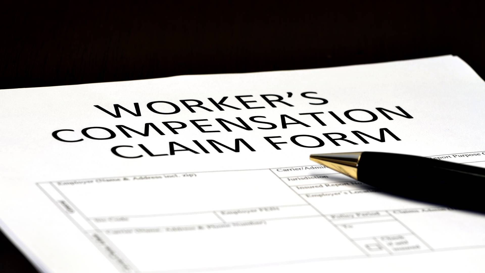 A pen is sitting on top of a worker 's compensation claim form.