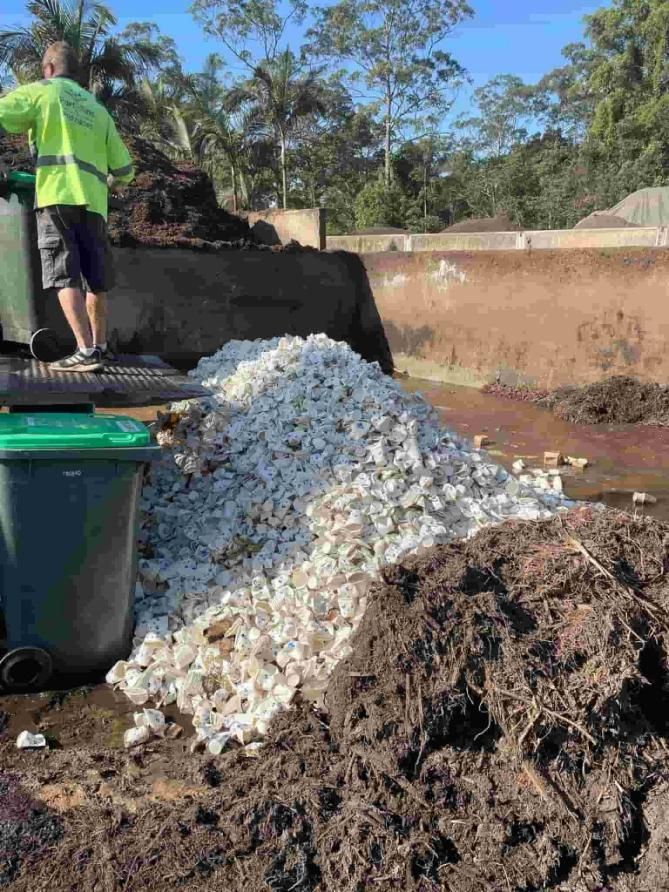 A Man Is Standing Next To A Pile Of Rocks In The Dirt — Party Bins Pty Ltd In Landsborough, QLD