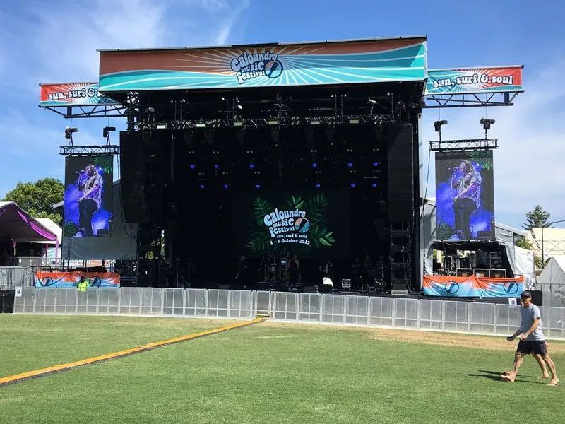 A Man Is Walking In Front Of A Large Stage At A Music Festival — Party Bins Pty Ltd In Landsborough, QLD