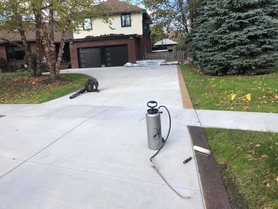 A brick house with a black garage door and a concrete driveway