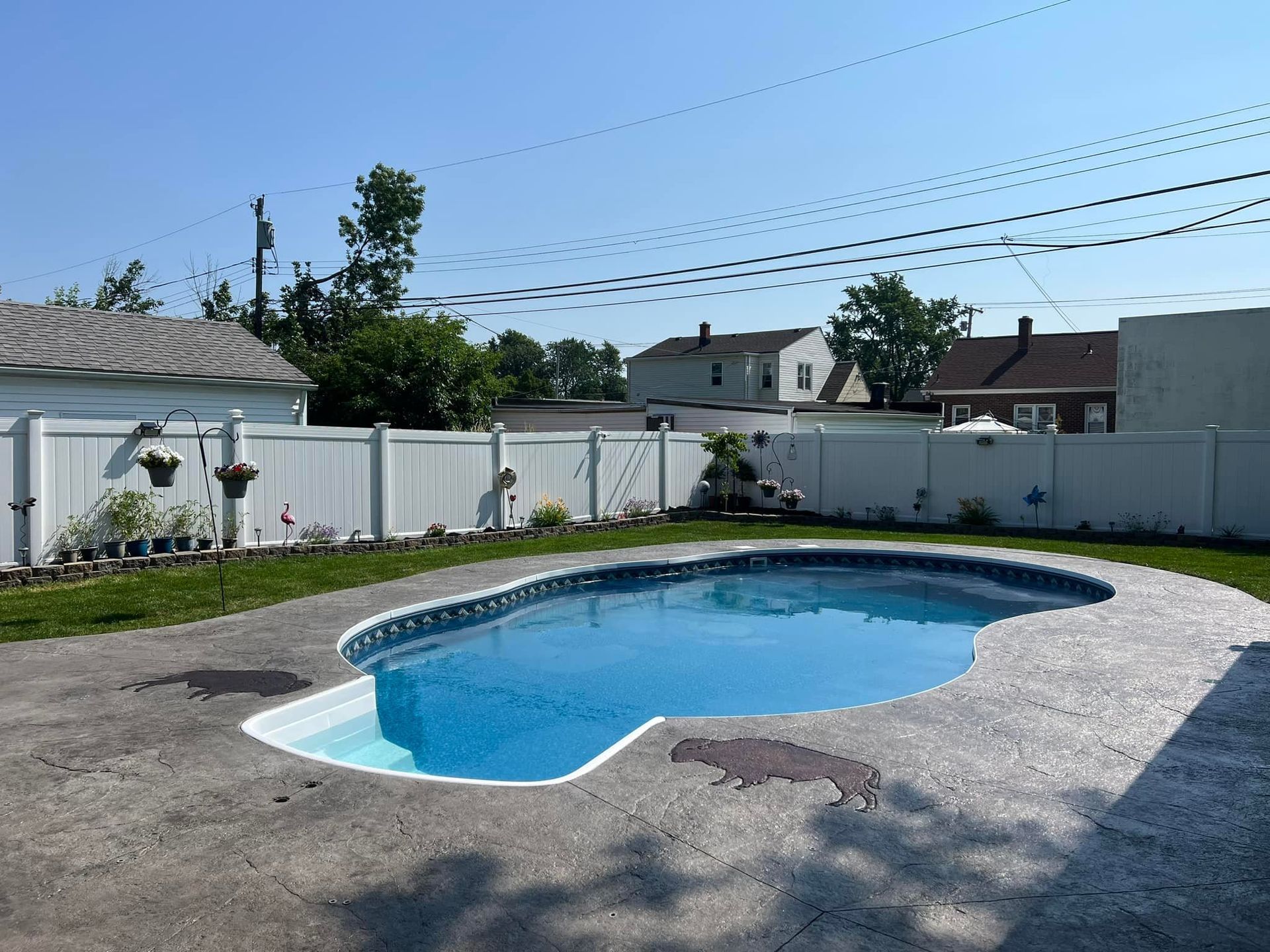A large swimming pool in a backyard with a white fence