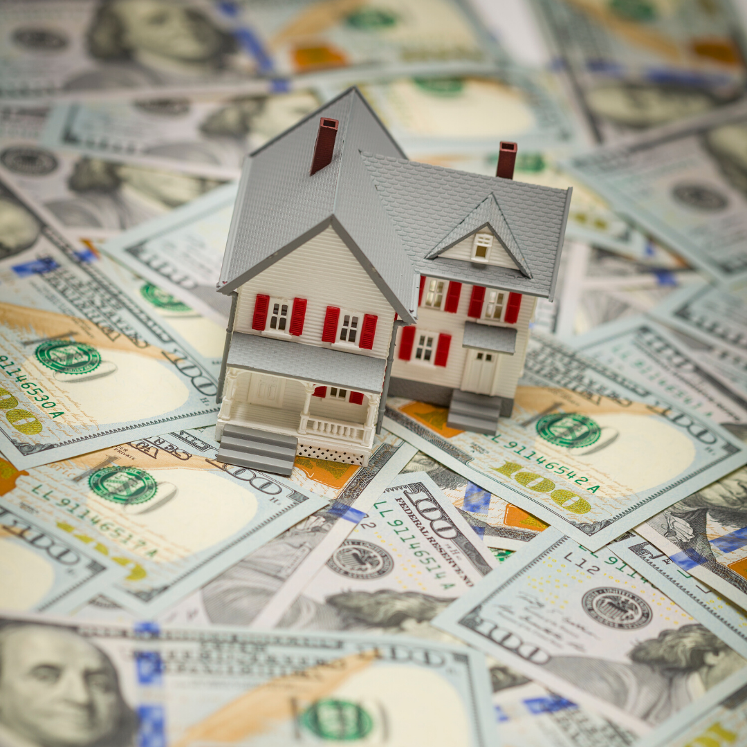 Image of a small scale house on top of money spread out.