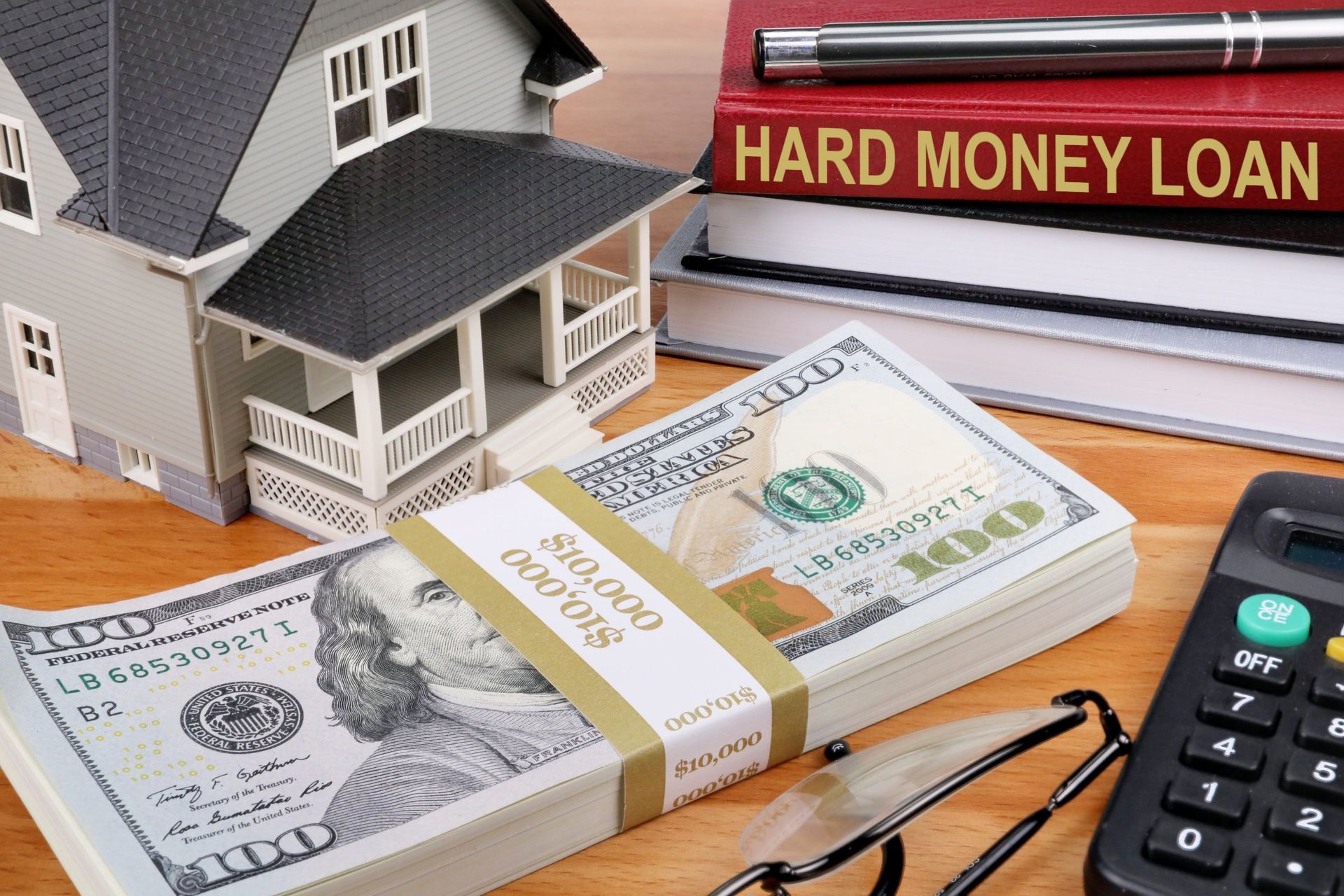 Image of a small scale house next a stack of money. Hard Money