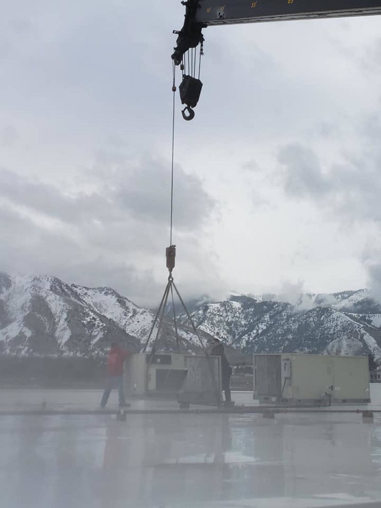 A crane is lifting a building with snowy mountains in the background