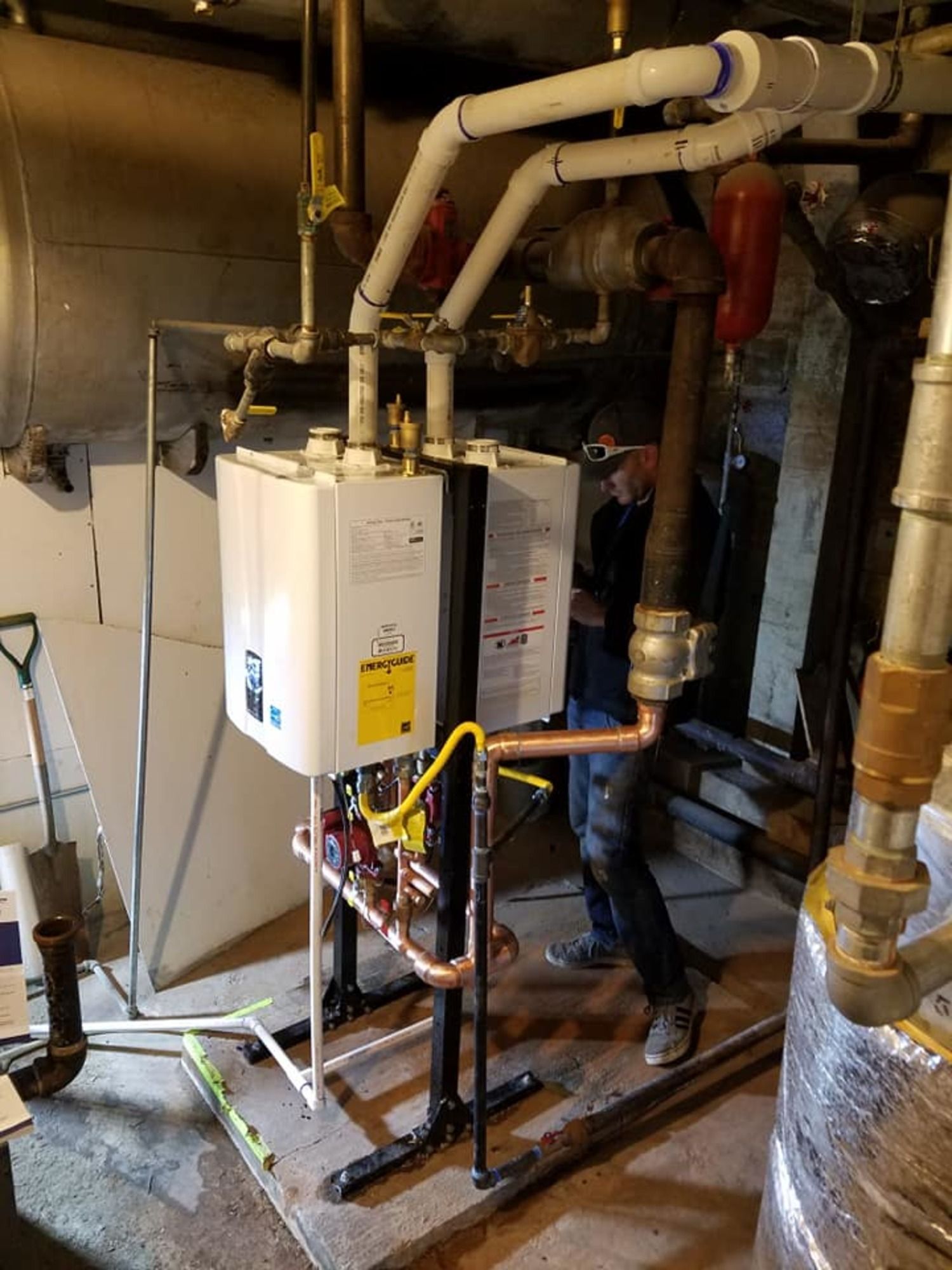 A man is working on a water heater in a basement.