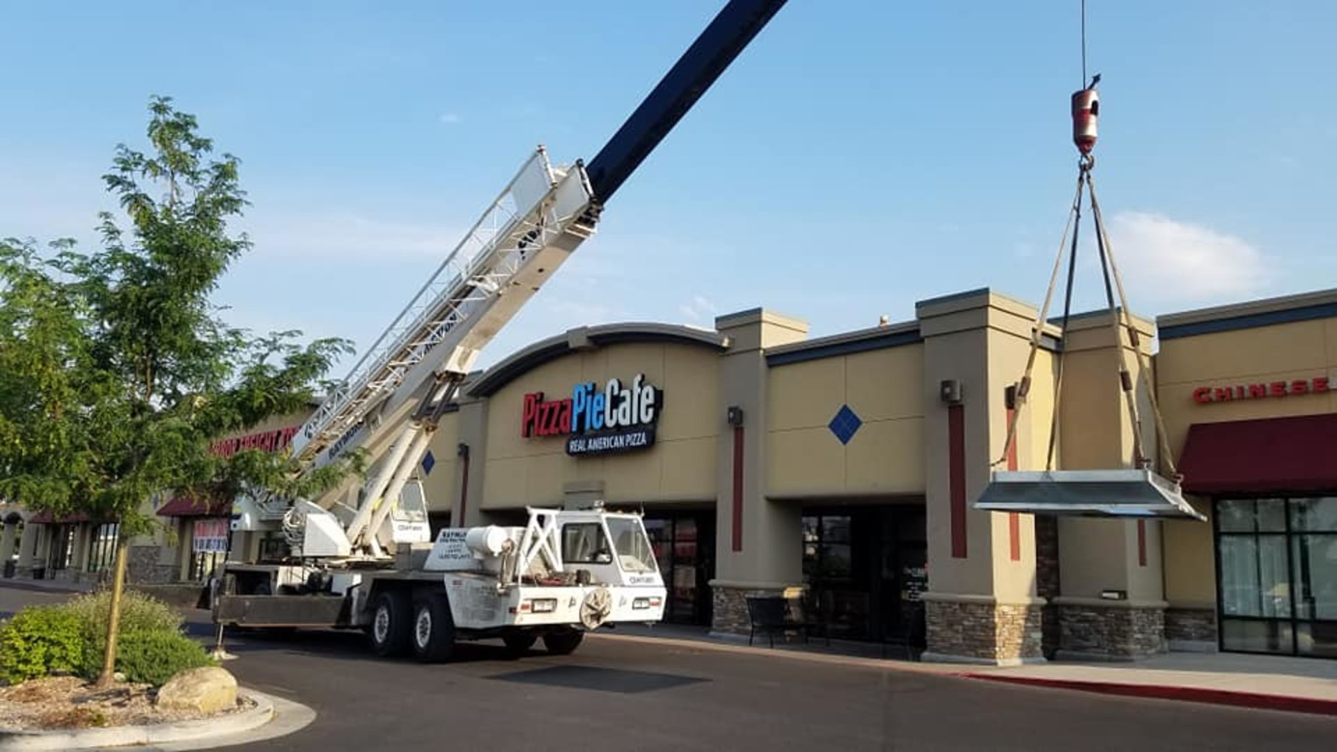A crane is lifting a canopy in front of a building that says rust-oleum