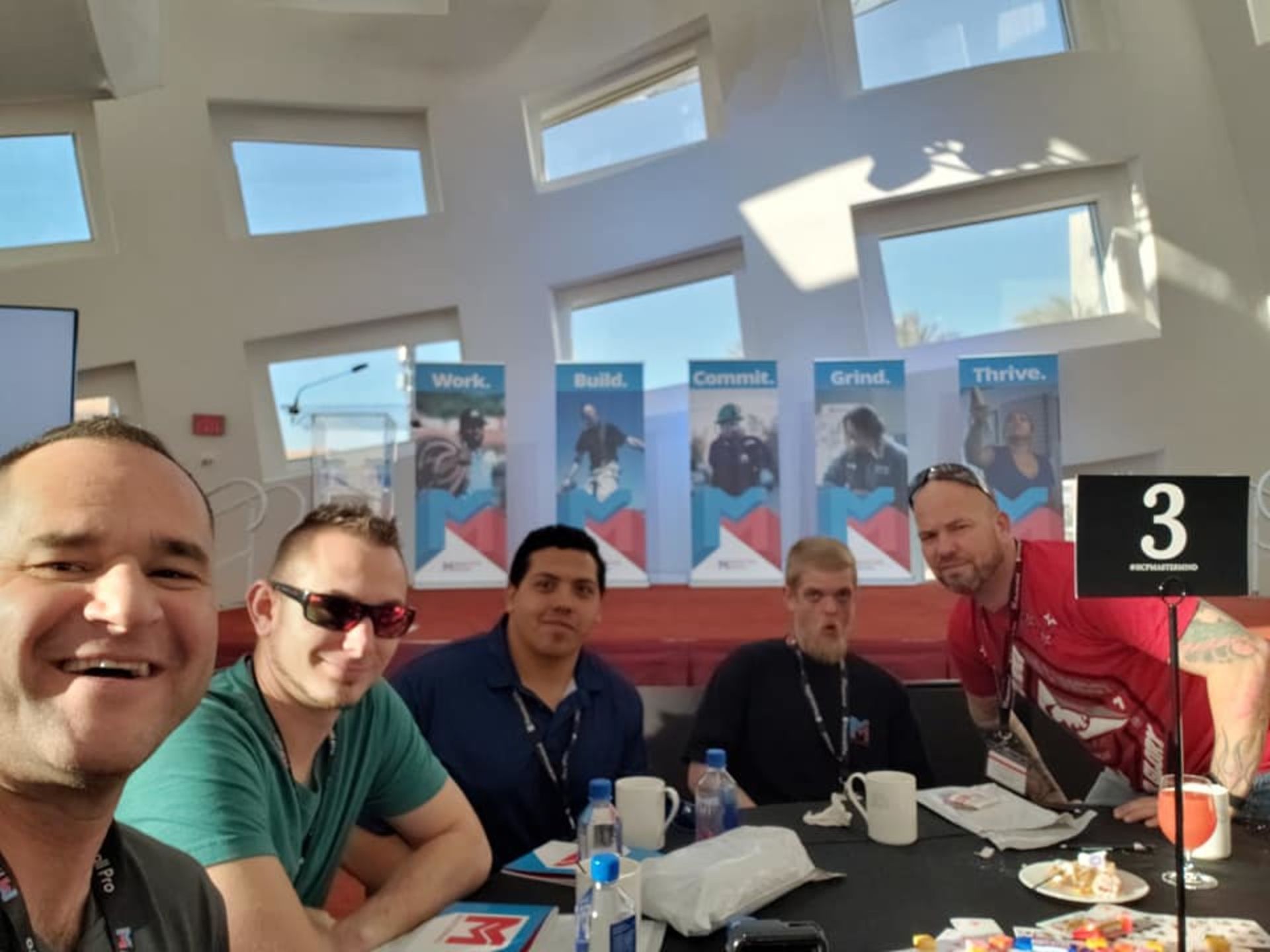 A group of men are sitting around a table with a sign that says 3