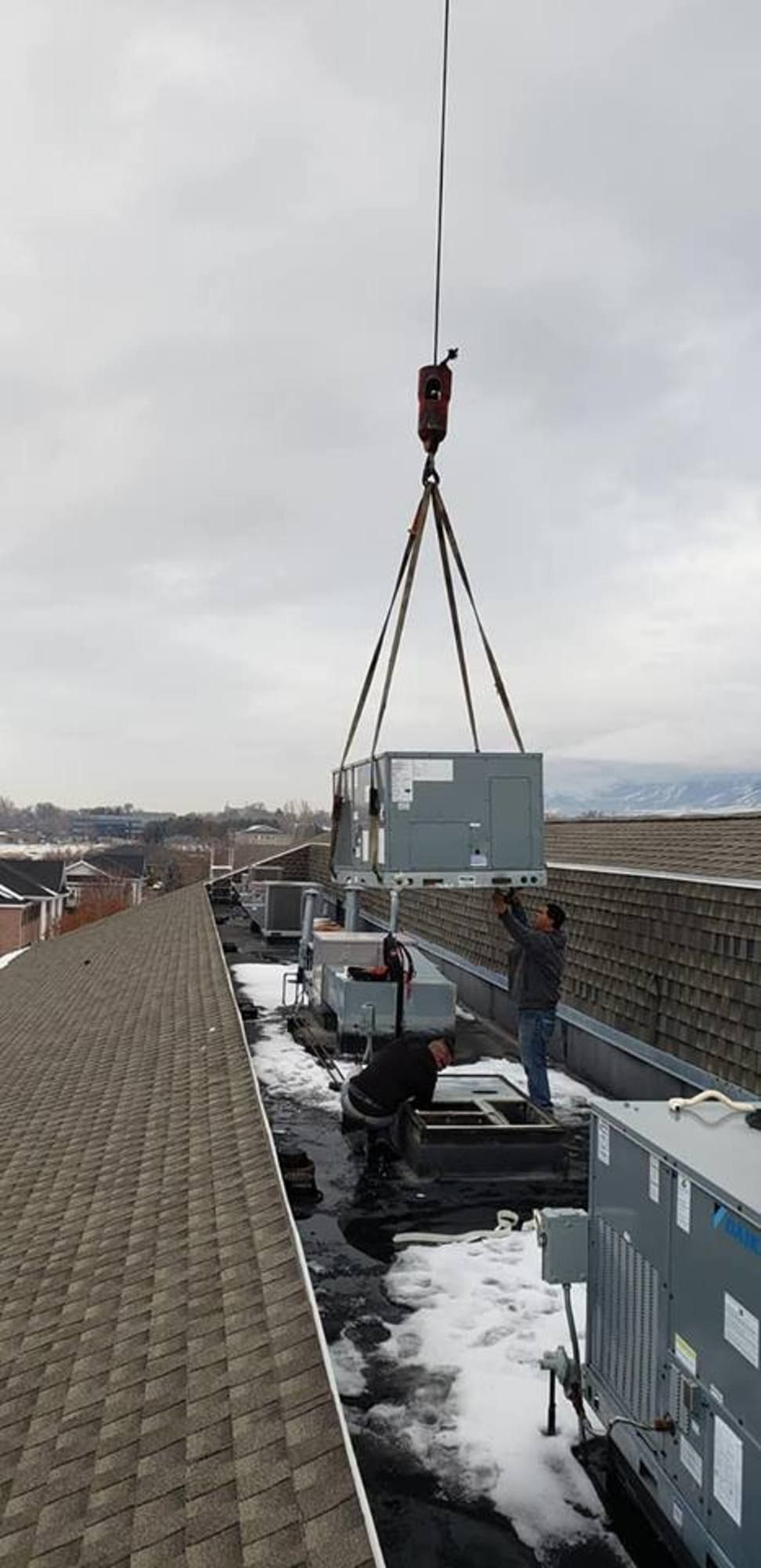 A crane is lifting a piece of equipment on top of a building.
