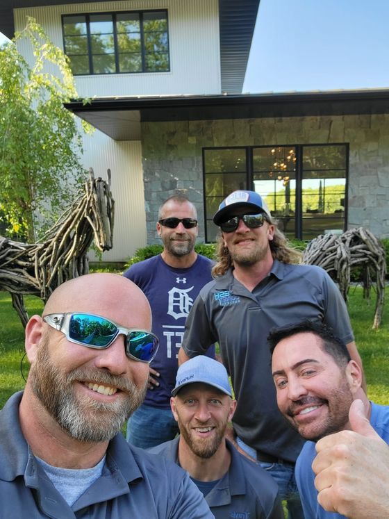 A group of men are posing for a picture in front of a house.